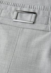 Hellgrauer Stoffbund mit gesammeltem elastischem Saum oben und rechteckiger silberner Metallschnalle, die an einem Stoffriemen befestigt ist.