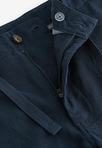 Pantaloni din bumbac de culoare albastru marin, cu fermoar, închidere cu nasture și snur. Prezentază o textură moale și detalii de cusătură subtile.