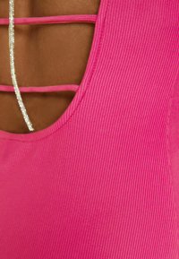 Body rose ajusté à côtes avec un décolleté large en forme de cœur, présentant un dos en croisillon et des accents argentés scintillants.