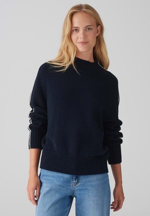 Navy blue knitted sweater with a high collar, ribbed hem, and cuffed sleeves featuring white side stripes. Soft texture and relaxed fit.