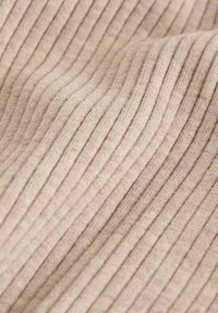 Ljust beige ribbat tyg med en mjuk textur, som har jämna vertikala ränder och en lätt stretch för komfort.