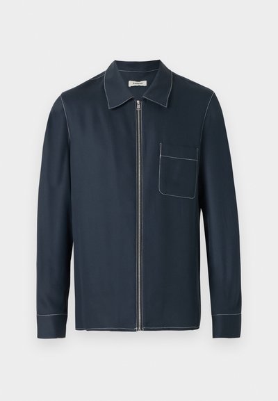 Μπλε ναυτικό μακρυμάνικο πουκάμισο-σακάκι με γιακά, μπροστινό φερμουάρ, μία τσέπη στο στήθος και λευκή αντίθεση ραφών στις ραφές και τις άκρες.