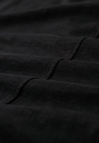 Black fabric with a soft texture, featuring evenly spaced folds, providing a subtle ribbed pattern across the surface.