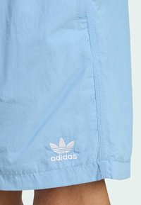 Light blue shorts made from lightweight fabric, featuring white stitching and a small white embroidered Adidas logo at the hem.
