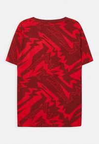 Rode T-shirt met korte mouwen en een gedurfde zigzagpatroon in verschillende tinten rood. Gemaakt van gestructureerde katoenstof en voorzien van een ronde hals.