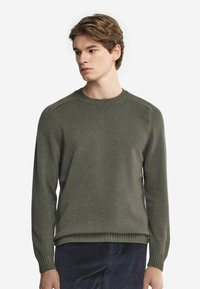 Olivgrön stickad tröja med rundad halsringning, ribbade ärmslut och nederkant; har en slät yta och en lätt avslappnad passform.
