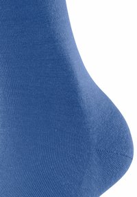 Primo piano di una calza blu morbida che mette in risalto il suo tessuto testurizzato e le curve morbide, evidenziando il colore e la qualità del materiale.