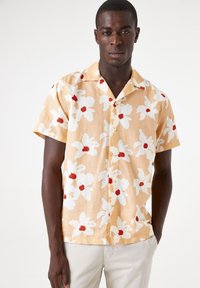 Korte mouwen, knoopsluiting in lichtgeel met groot wit en rood bloemenpatroon, katoen stof, relaxte pasvorm, opgestikte kraag.