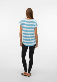 Striped blue and white short-sleeve top with a rounded hem, paired with black skinny jeans and flat sandals. Simple design, casual fit.