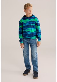 Felpa con cappuccio in motivo tie-dye blu e verde, maniche lunghe. Indossata con jeans azzurri e sneaker nere.