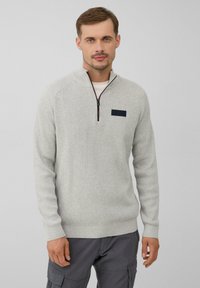 Hellgrauer gestrickter Pullover mit einem Reißverschlusskragen, der ein texturiertes Muster und einen dunklen Fleck auf der linken Brust hat. Getragen zu grauen Cargo-Hosen.