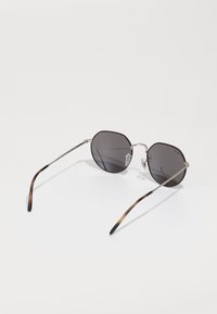 Ochelari de soare rotunzi cu lentile întunecate, model de broască țestoasă pe ramele tacate, teme subțiri din metal argintiu și un finisaj lustruit.