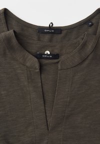 Dark olive green blouse with a split round neckline and visible Opus brand label inside collar, size 36 tag on shoulder seam.