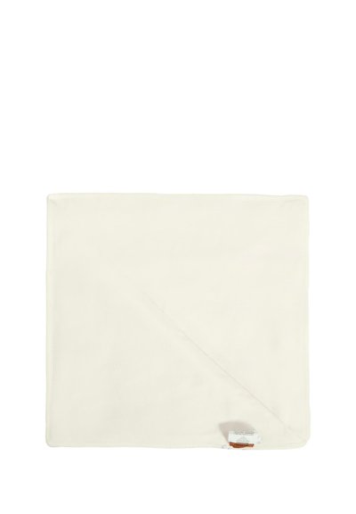 Jasnokremowy koc uszyty z miękkiego materiału, o kwadratowym kształcie, z delikatną teksturą i metką w jednym rogu.