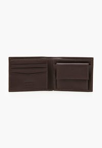 Brown leather wallet interior with multiple card slots, a pocket for bills, and a snap closure compartment for additional storage.