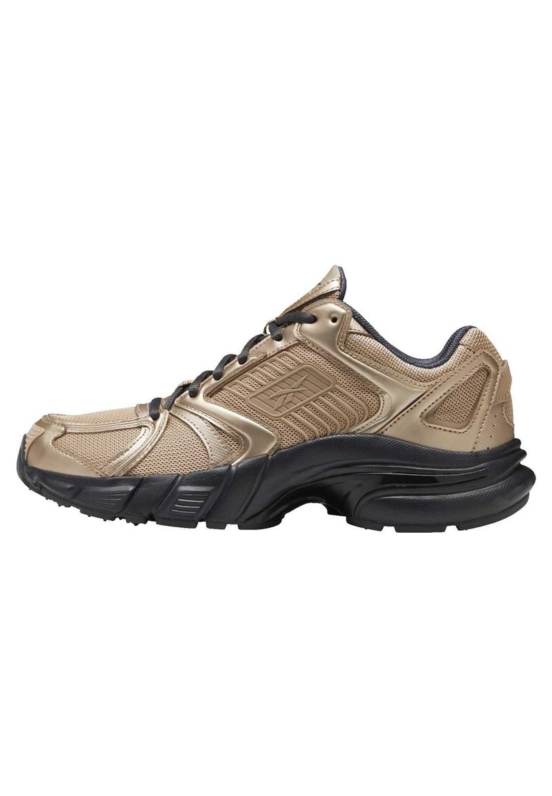 Baskets de sport beige et noires avec dessus en mesh et synthétique, lacets noirs, col rembourré et semelle extérieure épaisse noire texturée.