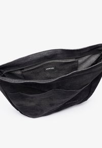 Black tote bag with a zippered top, spacious interior, and external pockets. Brand label "YOURTURN" visible inside.