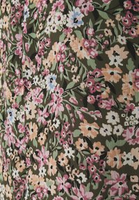 Tejido floral con pequeñas flores multicolores en rosa, blanco y azul sobre un fondo verde oscuro con textura acanalada.