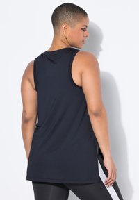 Musta hihaton urheilu-tank top, kevyt kangas, hienoinen kiilto, tiukka olkapäiltä, rento istuvuus, sivuaukot liikkumisen helpottamiseksi.