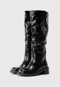 Botas negras hasta la rodilla hechas de material sintético brillante. Presentan un diseño holgado, punta redondeada y un tacón bajo.