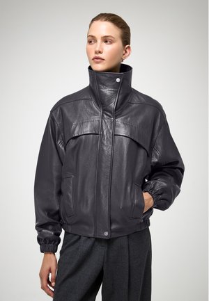 Dark gray leather jacket with a high collar, elastic cuffs, and front pockets. Features stitched detailing and a glossy texture.