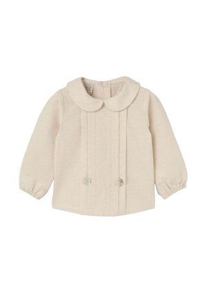 Blouse en tissu tissé beige clair, avec un col rond, de longues manches bouffantes, des accents en dentelle sur le devant et une fermeture à deux boutons.