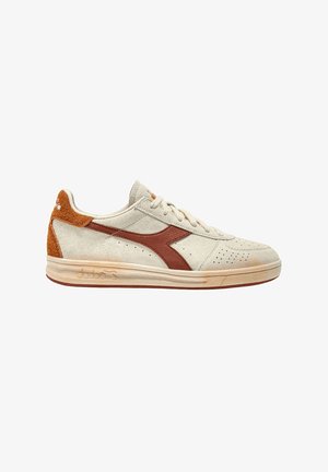 Sneaker in suede beige con dettagli in pelle marrone e forature. Presenta un tallone testurizzato e una suola in gomma. Logo del marchio sui lati.