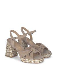 Sandales à talons en suede beige avec un détail noué à l'avant, une bride de cheville et un talon tissé texturé. Présente une semelle compensée.