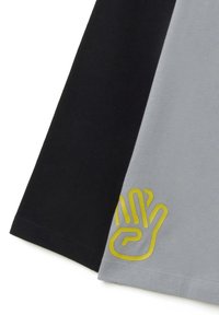 Korte mouw shirt met zwart en grijs kleurvakken, met een gestructureerde gele handgrafiek op het grijze gedeelte. Zacht katoenen materiaal.