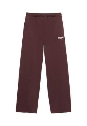 Pantalon de survêtement marron foncé à jambes larges avec taille élastique et petit logo blanc "stockholm couture" sur la cuisse gauche supérieure.
