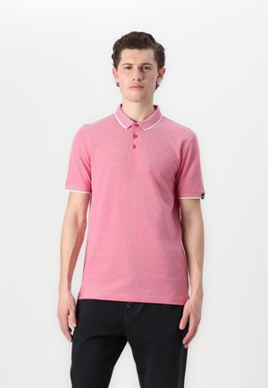Rosa Poloshirt aus Baumwollmischung, mit einem Kragen mit weißem Besatz, drei Knöpfen und kurzen Ärmeln. Getragen mit dunklen Jeans.