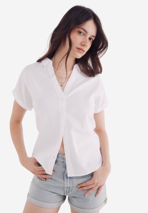Witte korte mouwen button-up shirt met een kraag, textuurstof en een relaxte pasvorm, gecombineerd met lichte denim shorts.