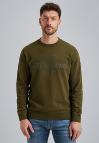 Sweatshirt verde oliva con scollo a girocollo, polsini e orlo a costine. Presenta grafiche testurizzate e tenui in un design circolare sulla parte anteriore.