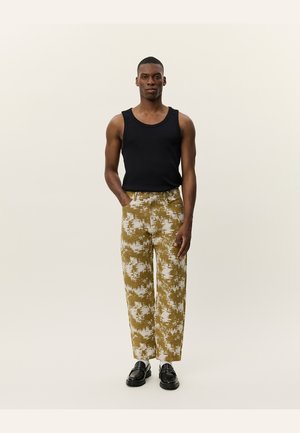 Black tank top paired with patterned, loose-fit pants in earthy tones of mustard and white, featuring an elastic waistband and straight cut.
