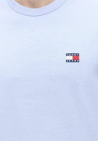 Ανοιχτομπλε T-shirt με στρογγυλή λαιμόκοψη και μικρό λογότυπο Tommy Jeans σε κόκκινο, λευκό και ναυτικό μπλε στο αριστερό στήθος.