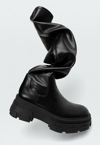 Zwarte leren enkelboots met een dikke, robuuste zool en een elastische zijkant. Voorzien van een gedraaide zwarte leren accent aan de bovenkant.