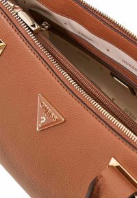 Sac à main en similicuir marron texturé avec ferrures dorées, doté d'un accent logo triangulaire et d'une ouverture zippée.