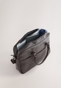 Braune Laptop-Tasche aus Leder mit zwei Griffen, Reißverschluss oben und Außentasche. Enthält einen Laptop, ein Notizbuch und eine Wasserflasche.