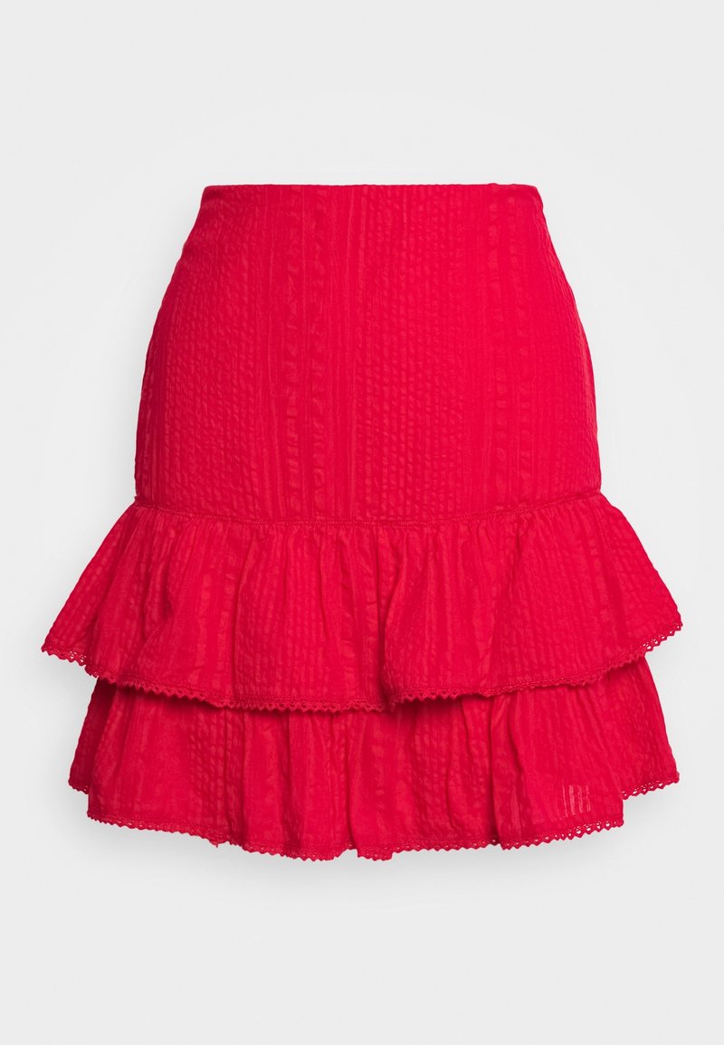 Jupe mini texturée rouge avec un ourlet à volants en deux niveaux et délicate bordure en dentelle sur les couches, le tout sur un fond clair et uni.