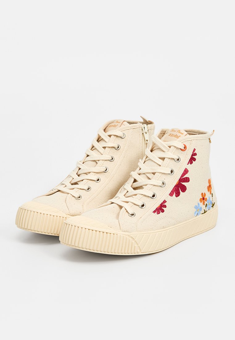 Baskets montantes en toile beige avec fermeture à lacets, fermeture éclair sur le côté, semelles en caoutchouc nervuré et broderie florale multicolore sur les côtés extérieurs.
