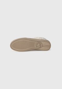 Semelle de sneaker en toile beige avec des caractéristiques de grip texturé. Détail de logo circulaire sur le talon. Design lisse et plat avec une légère courbure.
