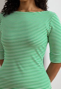 Green and white striped shirt with a boat neckline and three-quarter sleeves, made of a soft, stretchy material. Smooth texture.