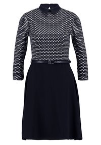 Robe marine avec un haut à motifs cœur, manches longues, col, et une taille cintrée avec une ceinture noire au niveau des hanches.