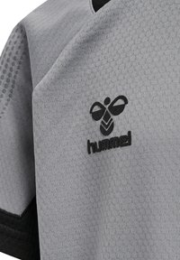 Grijze sporttrui van textuurstof met een hexagonaal patroon, voorzien van een zwart logo en rand langs de halslijn en mouwen.
