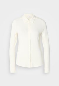 Chemise blanche à manches longues avec col et boutons, présentée sur un fond clair uni.