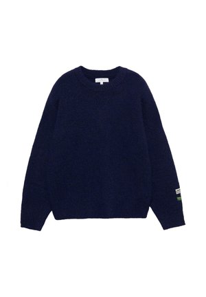 Pull en maille bleu marine avec un col rond, une coupe ample et des poignets côtelés. Il comporte une petite étiquette sur la manche gauche.