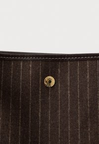 Rudas dryžuotas audinys maišas su auksiniu užsegimu. Yra juodos odos apdaila ir balta siūlė kraštuose. Paprastas ir funkcionalus dizainas.