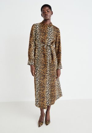 Kjole med leopardmønster som har lange ermer, kragehals, belted midje og en flytende silhuett i brune og beige toner.