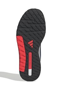 Black rubber shoe sole with a textured tread pattern, featuring a red accent and white label reading “DUAL DENSITY.”