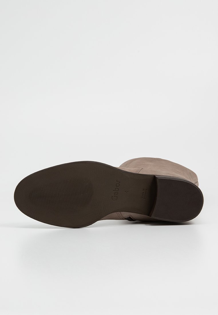 Bruine suede enkellaars met een lage hak en een ronde neus. Beschikt over een gestructureerde zool voor grip en reliëfbranding op de hak.
